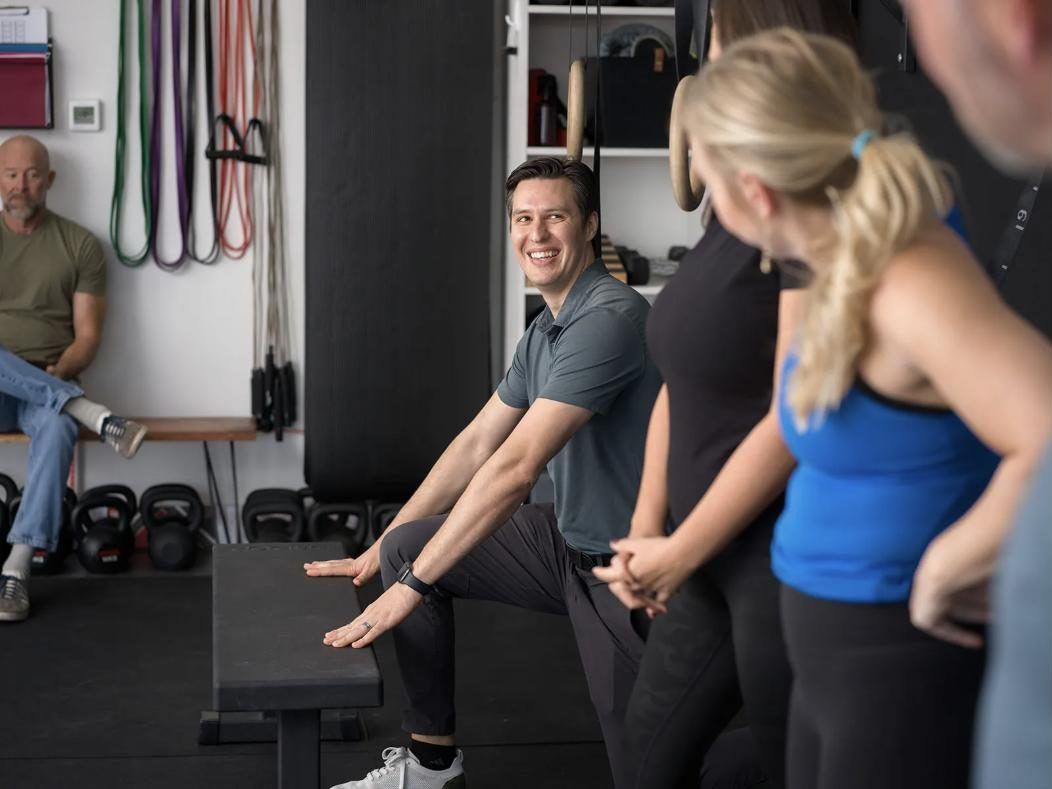 Dr. Golbek coaching a small group through a hip stretch on the gym floor at Movement Cube Fitness in Catoosa